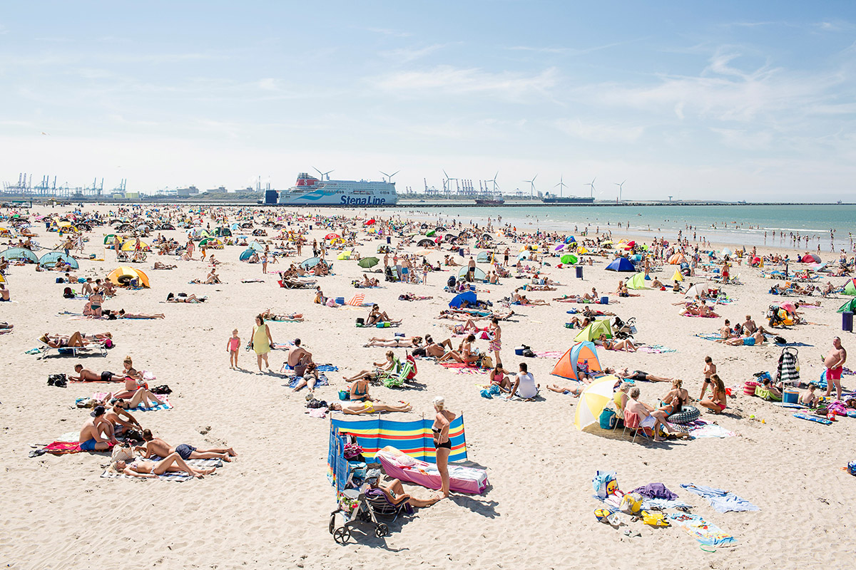Strand, Hoek van Holland, 2015<br>
Peter de Krom (1981), Rotterdam<br>
Peter de Krom verhuisde in 2010 weer voor vijf jaar naar 'De Hoek' waar hij eerder al 25 jaar lang had gewoond. Hij typeert Hoek van Holland als 'een vergankelijk dorp dat soms lijkt te verkeren in een identiteitscrisis. De bewoners voelen zich er vrij, maar zoeken tegelijk naar houvast. Er heerst een 'doe maar gewoon, dan doe je al gek genoeg'-mentaliteit.'<br>
De Krom won met zijn persfoto's meermalen een Zilveren Camera en publiceerde in de NRC, Vrij Nederland en het online tijdschrift Vers Beton. In 2020 sloot hij zijn fotocarrière af met de solotentoonstelling Hoek van Holland in de Kunsthal.