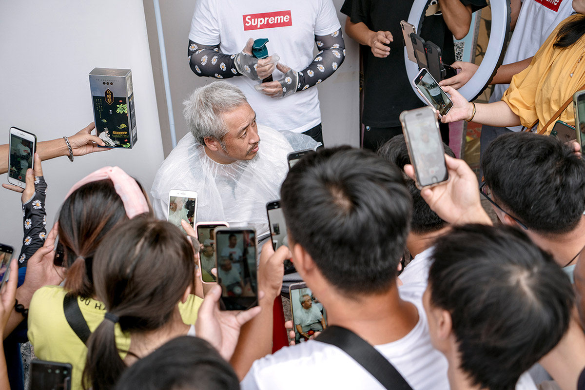 Ruben Lundgren, Yiwu, 2020, Man is ready to dye his hair on the street in the Beixiazhu district, where a complete shopping area for live- stream-vendors has sprung up under great interest. By filming with many at the same Ame, the product looks very popular and it might become a hit online.
