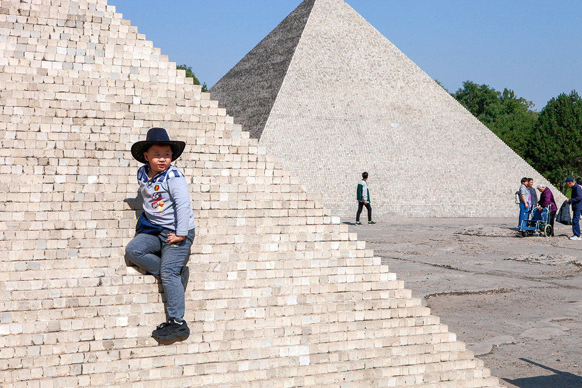 Ruben Lundgren, Beijing, 2017, A young visitor in the Beijing World amusement park on a miniature pyramid. The park opened in 1993 and provides an overview of iconic architecture in miniature. But the number of visitors has declined sharply in recent years, partly due to the growing middle class that now flies around the world to admire the original versions.