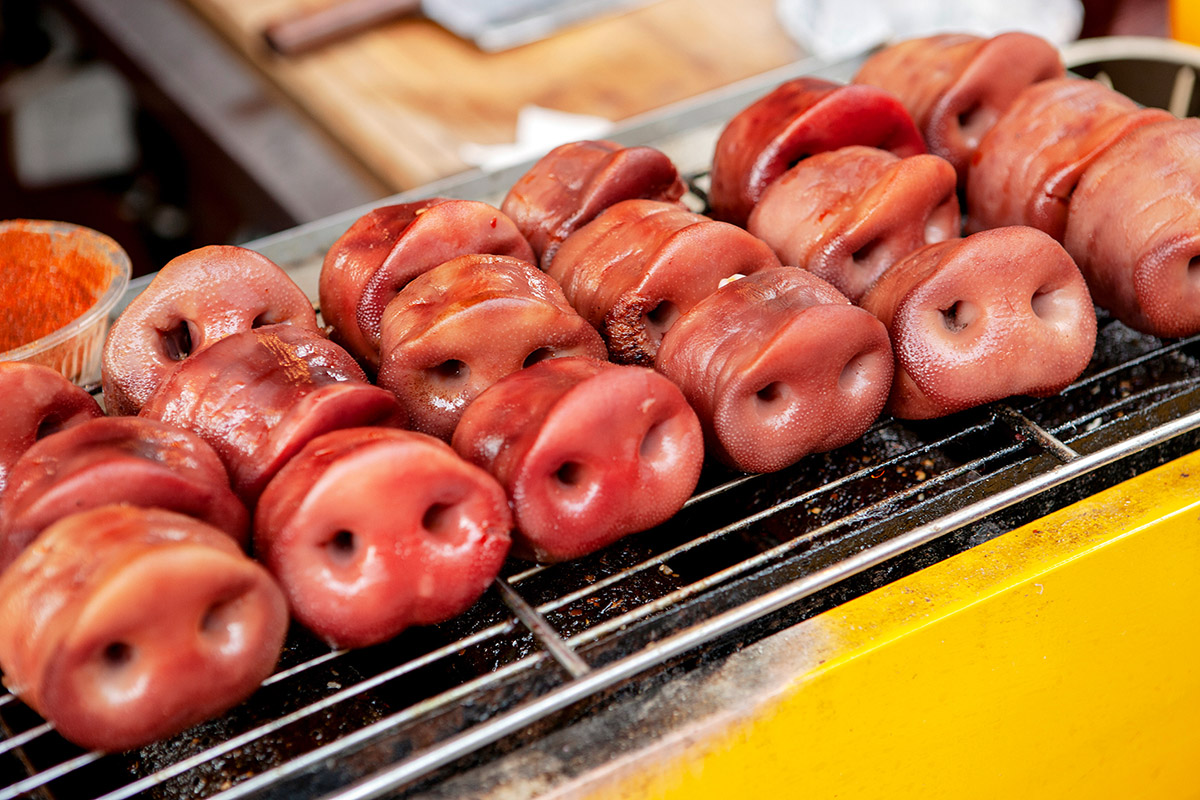 Ruben Lundgren, Chengdu, 2015, On the Kuanzhaixiangzi tourist food street, dozens of stalls and eateries promise Chengdu's best street snacks, including these grilled pork snouts. Other options include the marinade rabbit heads in spicy pepper, dried yak meat, and all sorts of snacks on sticks.