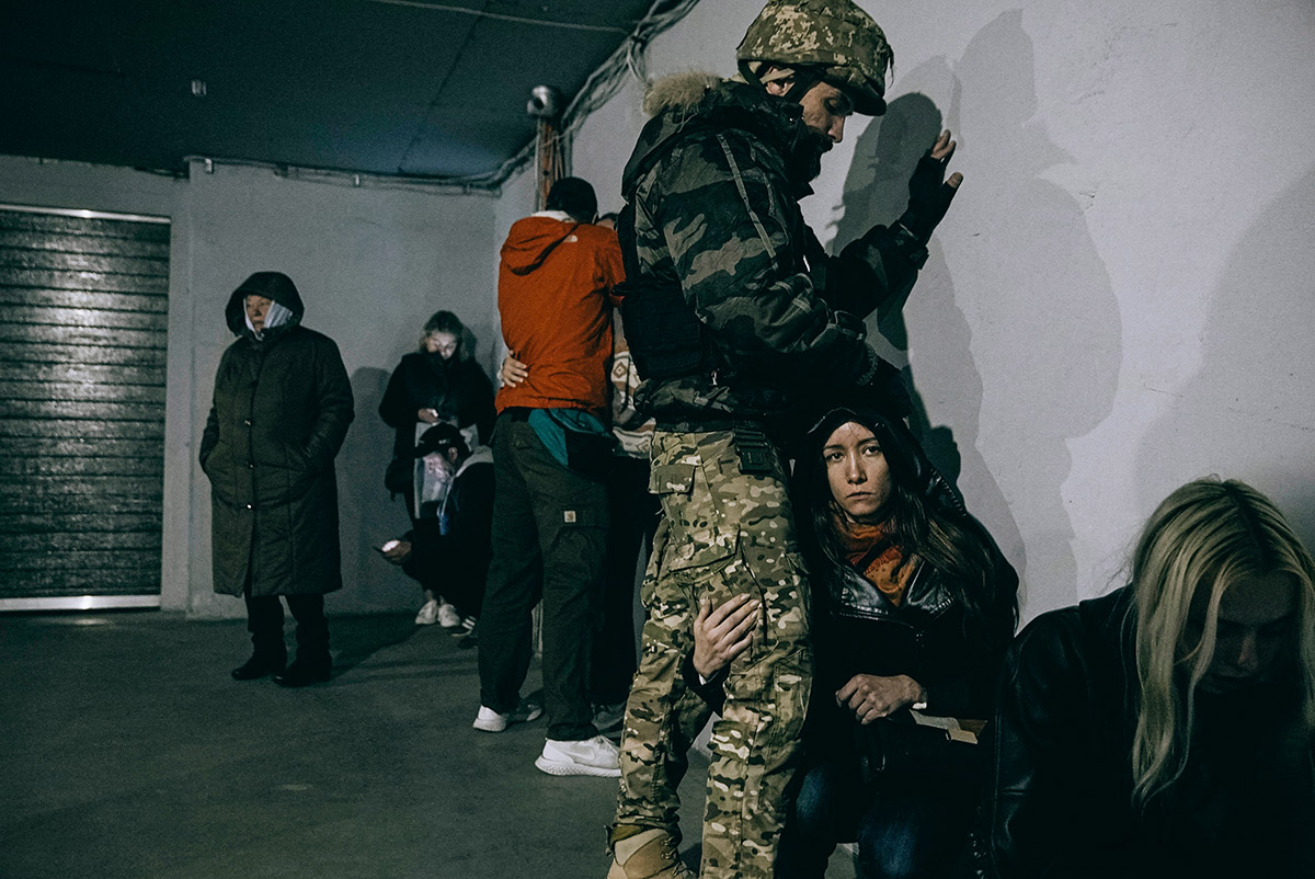 Julia Kochetova, A soldier protects a woman in an underground parking lot near the drone strike in Kyiv, 17 October, 2022