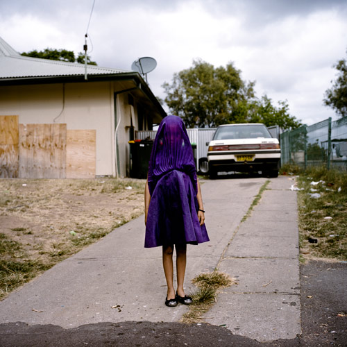 Raphaela Rosella, Australia, Oculi, First Prize Portraits Category, Singles. Moree, New South Wales, Australia, Laurinda waits in her purple dress for the bus that will take her to Sunday School. She is among the many socially isolated young women in disadvantaged communities in Australia facing entrenched poverty, racism, trans-generational trauma, violence, addiction, and a range of other barriers to health and well-being.